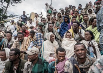 CORRECTION / People who fled the war from May Tsemre, Addi Arkay and Zarima gather around in a temporarily built internally displaced people (IDP) camp to receive their first bags of wheat from the World Food Programme (WFP) in Debark, 90 kilometres of the city of Gondar, Ethiopia, on September 15, 2021. (Photo by Amanuel Sileshi / AFP) / ìThe erroneous mention[s] appearing in the metadata of this photo by Amanuel Sileshi has been modified in AFP systems in the following manner: [Debark, 90 kilometres of the city of Gondar] instead of [Dabat, 70 kilometres northeast of the city of Gondar]. Please immediately remove the erroneous mention[s] from all your online services and delete it (them) from your servers. If you have been authorized by AFP to distribute it (them) to third parties, please ensure that the same actions are carried out by them. Failure to promptly comply with these instructions will entail liability on your part for any continued or post notification usage. Therefore we thank you very much for all your attention and prompt action. We are sorry for the inconvenience this notification may cause and remain at your disposal for any further information you may require.î